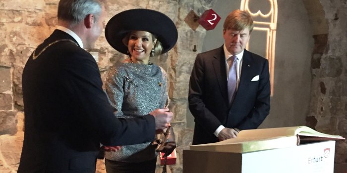 Das niederländische Königspaar steht mit dem Oberbürgermeister hinter einem Pult in der Alten Synagoge und trägt sich in das Goldene Buch der Landeshauptstadt Erfurt ein.