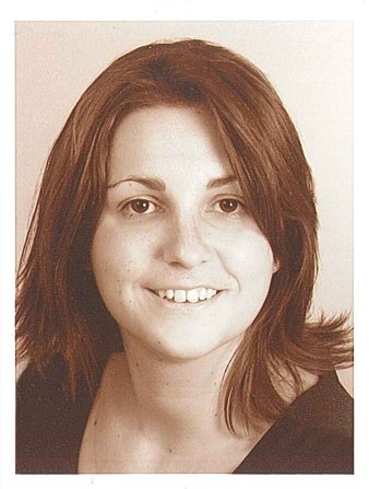 Eine junge Frau mit halblangen, glatten dunklen Haaren lacht mit offenem Mund in die Kamera. Das Foto ist eine Schwarz-weiß-Aufnahme mit altmodisch anmutendem Sepiaton.