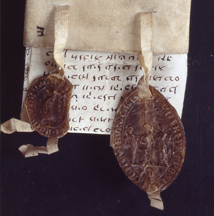 auf dunklem Hintergrund ist eine auf Hebräisch verfasste pergamentene Urkunde mit zwei wächsernen Siegeln