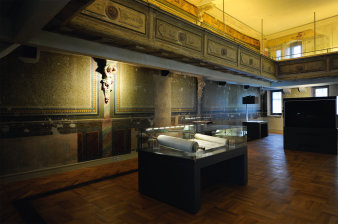 Festively decorated and painted room with circular gallery with showcases exhibiting manuscripts