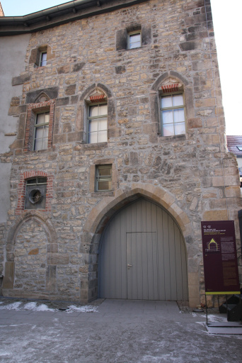 Blick auf die Nordfassade mit drei erhalten Lanzettfenstern, der zugemauerten alten Eingangstüre und dem Tor rechts daneben, das als Zufahrt zum Lagerhaus geschaffen wurde.