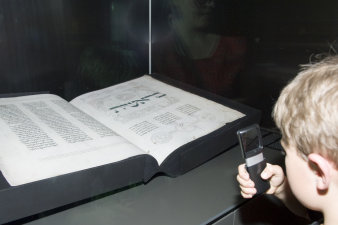 Junge betrachtet mit Hilfe einer Lupe eine hebräische Handschrift in der Ausstellung der Alten Synagoge