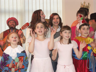 Lachende und verkleidete Kinder mit Musiker im Hintergrund