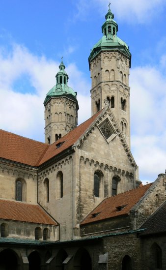 Zu sehen sind die Osttürme des Naumburger Doms vom Kreuzgang aus fotografiert; zwei gotische Kirchtürme vor blauem Himmel.
