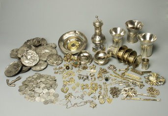 Der gesame Schatzfund ausgebreitet und sortiert in seine einzelnen Bestandteile. Münzen, Silberbecher, Silberbarren, Schmuck in diversen Arten.