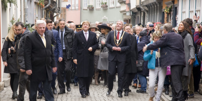 Das Königspaar auf der Krämerbrücke, zahlreiche Fotografen und Erfurter erwarten die Gäste. König Willem-Alexander, der Oberbürgermeister und der Ministerpräsident gehen voran, dahinter folgen Máxima, Vertreter des Hofes und weitere Gäste. 