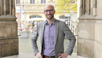 ein junger Mann mit Brille stemmt die Hände in die Hüfte