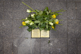 neben zwei im Boden eingelassenen Messingsteinen liegen gelbe und weiße Rosen