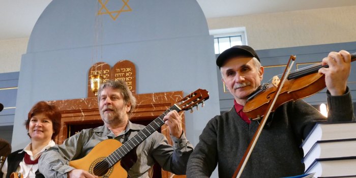 Zwei Männer und eine Frau mit Instrumenten, im Hintergrund Toraschrein der Neuen Synagoge Erfurt