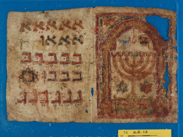 Ein altes Schriftstück aus Pergament mit hebräischen Schriftzeichen und der Illustration einer Menorah.