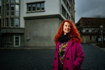 Frau mit roten Haaren und pinken Mantel vor dem Erfurter Rathaus