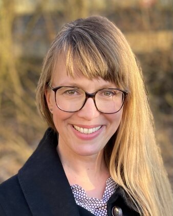 Portrait einer blonden Frau mit Brille die lächelt