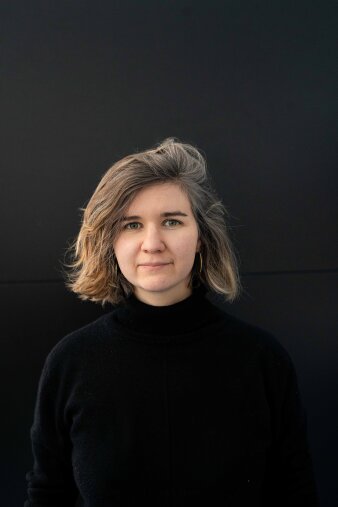 Junge Frau in schwarzer Kleidung vor einem schwarzen Hintergrund