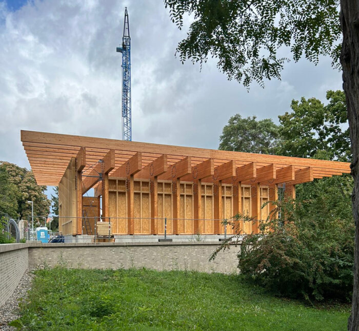 Gebäude mit hellen Holzbalken in der Bauphase samt Kran