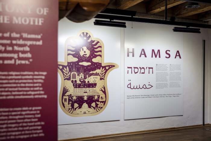 Schautafeln in einer Ausstellung mit Schriftzug und Bildmotiv in Rottönen