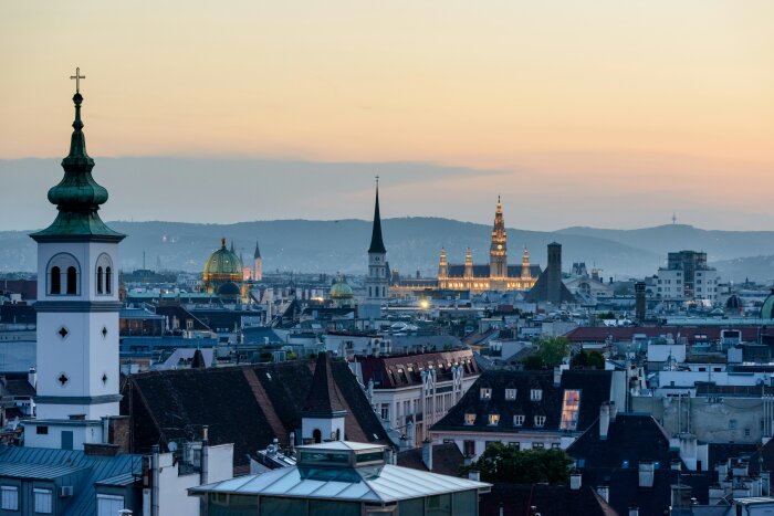 Luftaufnahme einer Stadt mit Türmen und Dächern bei Sonnenuntergang