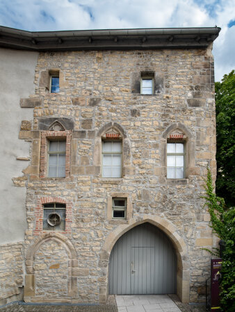 Backsteingebäude mit Torbogen, Holztür und mehreren Fenstern