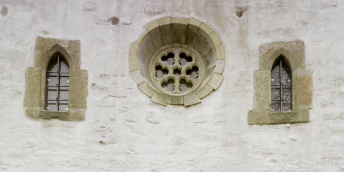 Detail of the facade. A large rose window is flanked by two smaller lancet windows.