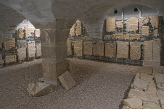 Kellergewölbe mit historischen Grabsteinen, die an der Wand aufgereiht sind