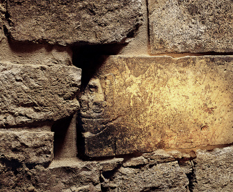 Illuminated detail of the wall of the medieval mikveh that shows an upside down, bricked-in sculpture from the 12th century