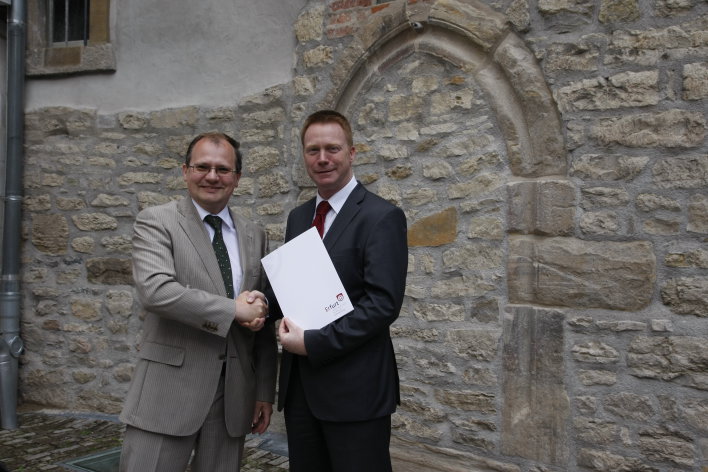 In front of the Old Synagogue's northern facade, the Deputy Mayor for Construction and Traffic, Mr. Ingo Mlejnek, submits the Statement of Outstanding Universal Value to the Thuringian Minister for Education, Science and Culture, Mr. Christoph Matschie.