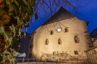 die Nordansicht der Fassade der alten Synagoge unterm dunklen Nachthimmel mit spärlich verputzter Bruchsteinmauer