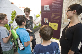 Julia Roos erklärt einer Familie den Bau der Alten Synagoge anhand einer Ausstellungstafel.
