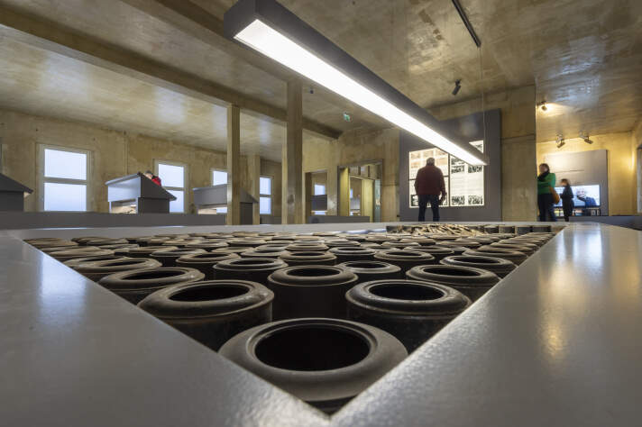 Erneuerte Dauerausstellung im Erinnerungsort Topf & Söhne Ausstellungsraum mit industriellem Ambiente und verschiedenen Schaukästen, Installationen und Besuchern