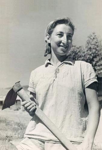 Schwarz-Weiß-Aufnahme einer Frau, die eine Harke in den Händen hält